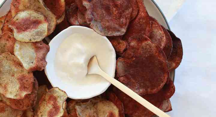 2 flavours of potato chips on a plate with dip in the middle
